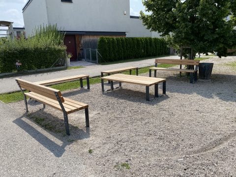 Hof mit Schotterplatz und modernen Sitzbänken aus Holz